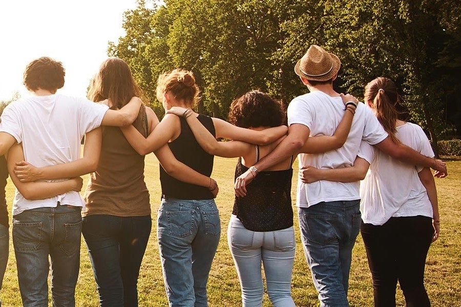A group of people standing in a row with their arms around each other's shoulders.